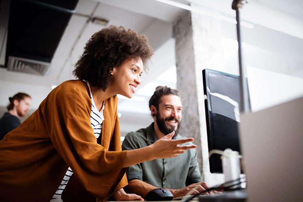 Customer support team collaborating at a computer in a modern office.