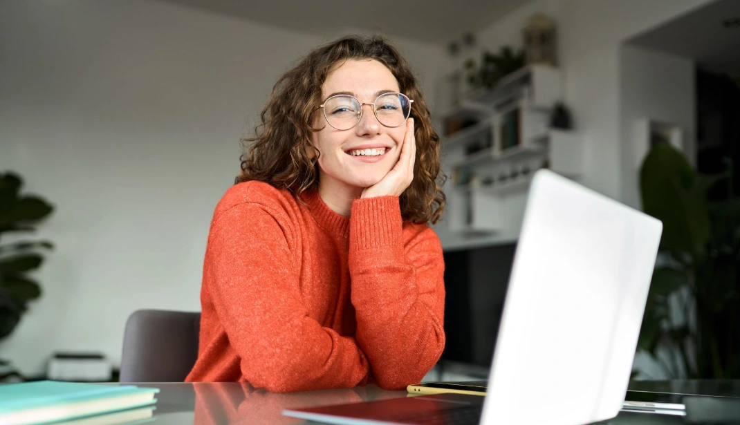 woman in red sweater with her laptop open smiling at the camera